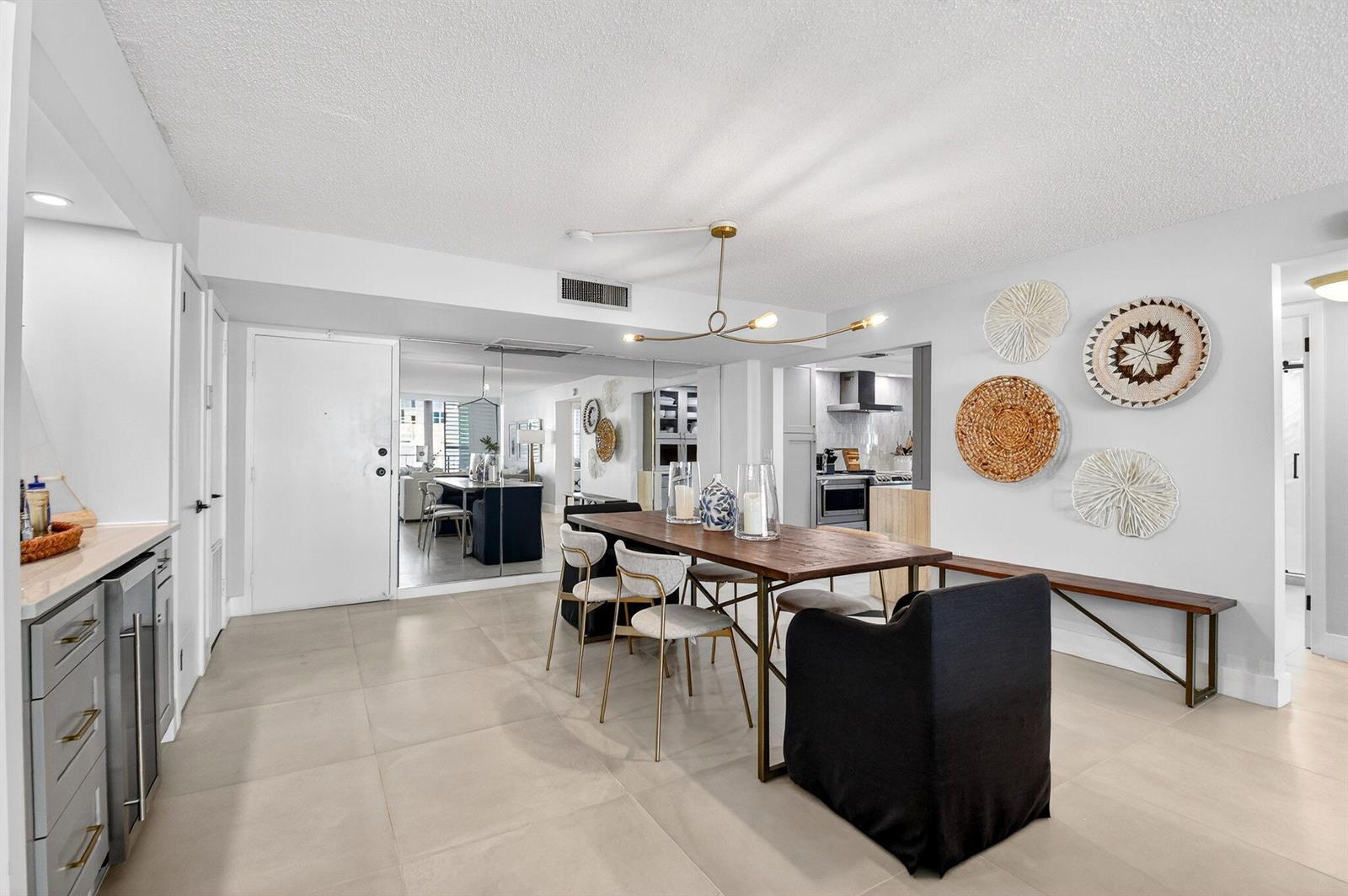 A dining area with a wooden table, chairs, a bench, and wall-mounted decorative woven plates — 3456 S Ocean Boulevard # 105, Palm Beach FL 33480, PALM BEACH, FL