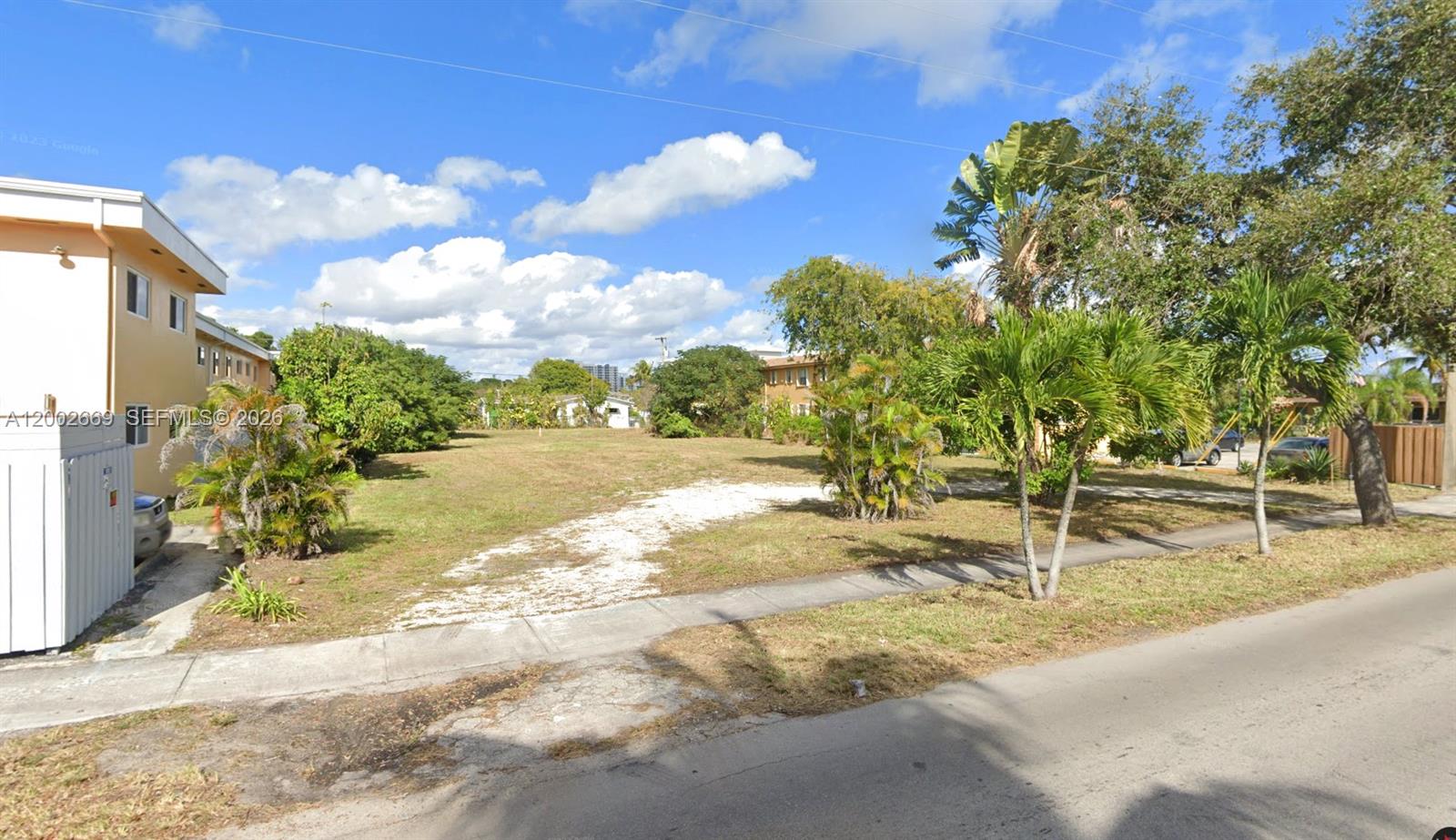 A vacant, grassy lot sits between two multi-story residential buildings along a paved street — 2239 Washington St, Hollywood FL 33020, HOLLYWOOD, FL