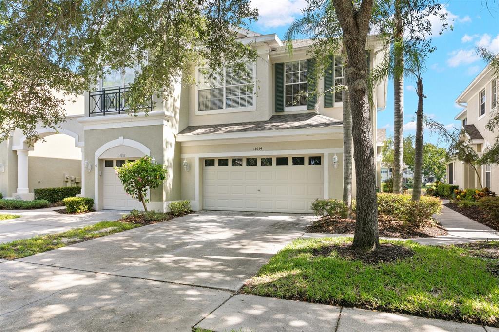 A two-story townhouse with a two-car garage, a balcony, and a concrete driveway — 14034 WATERVILLE CIRCLE, TAMPA, FL