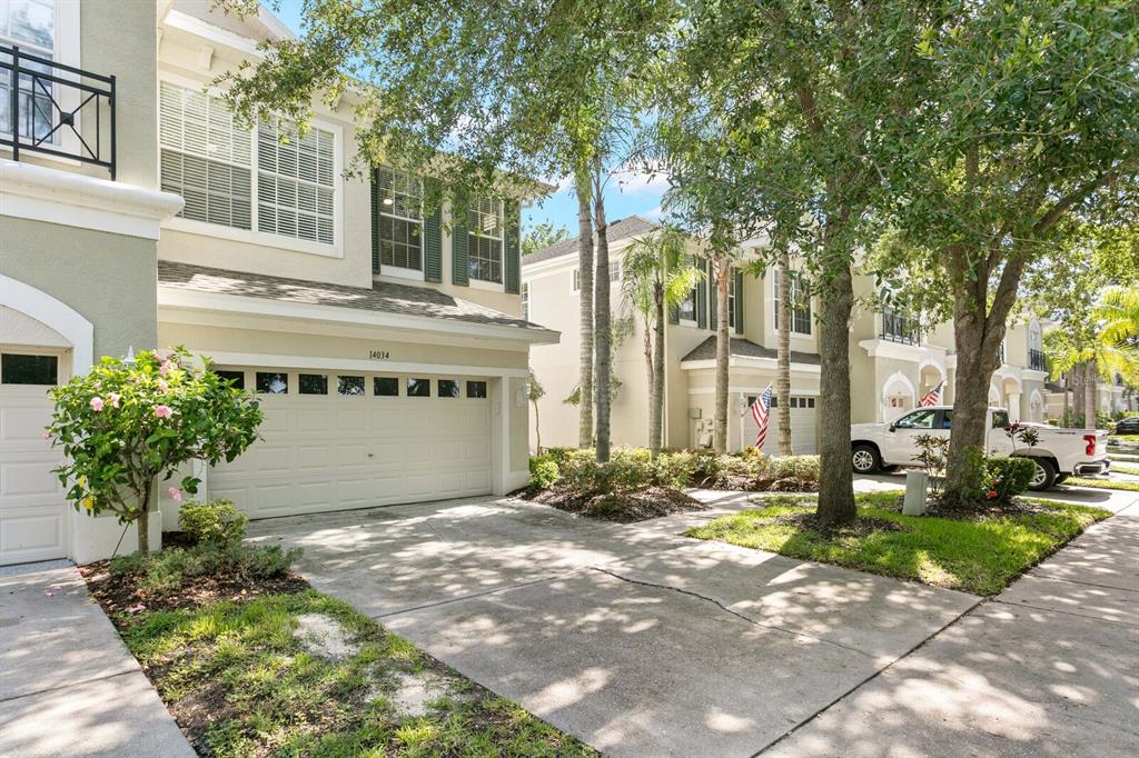 A two-story townhouse with a beige exterior, a two-car garage, and a concrete driveway — 14034 WATERVILLE CIRCLE, TAMPA, FL