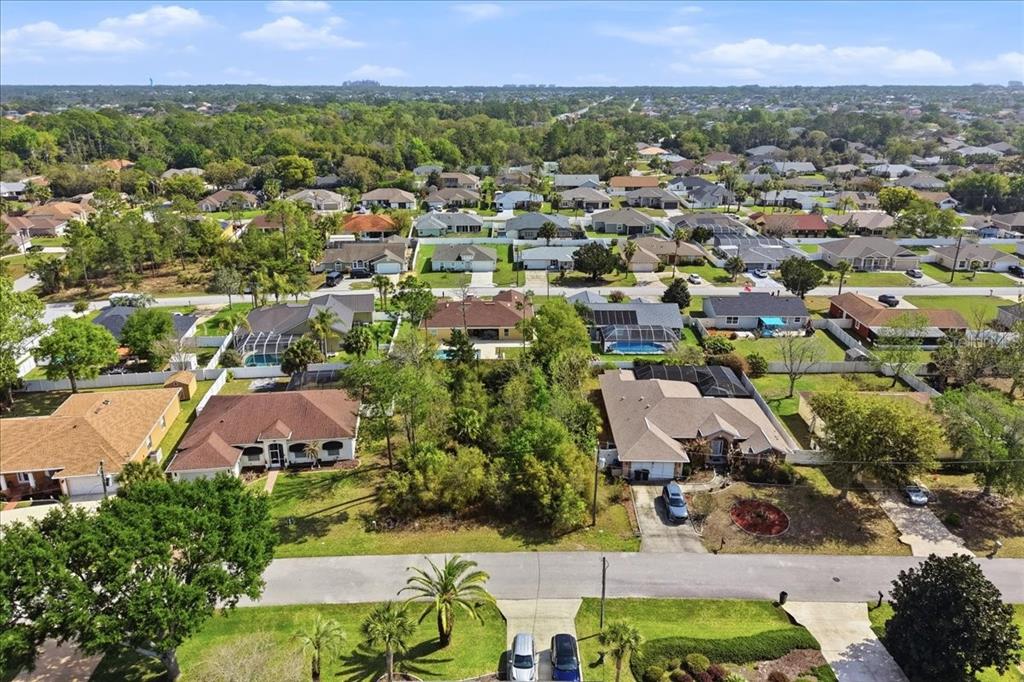 An aerial view shows a suburban neighborhood with single-family homes, green lawns, and mature trees — 95 FREEMONT, PALM COAST, FL