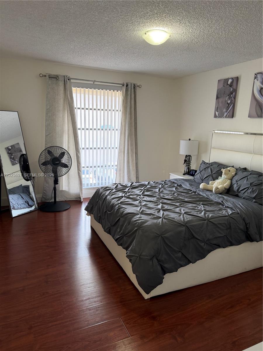 A bedroom features a bed with dark bedding, a floor mirror, and a window with blinds — 13789 SW 66th St # 283F, Miami FL 33183, MIAMI, FL