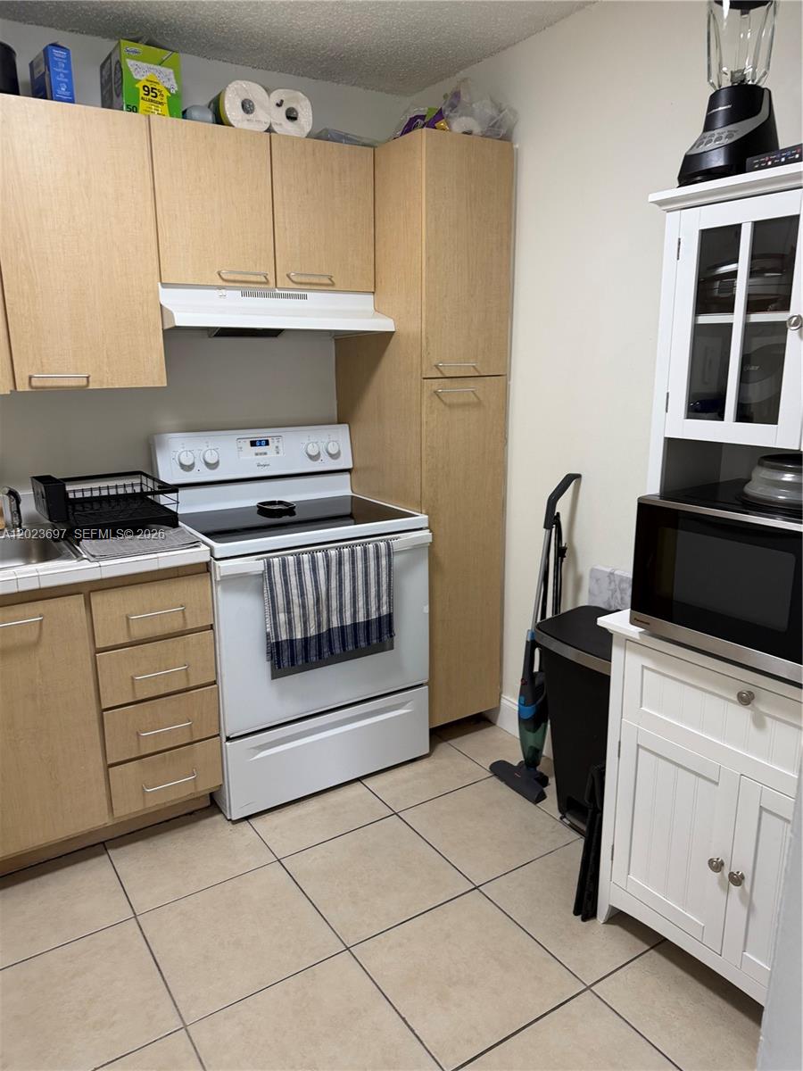 A kitchen features light wood cabinets, a white stove, and a white hutch with a microwave — 13789 SW 66th St # 283F, Miami FL 33183, MIAMI, FL