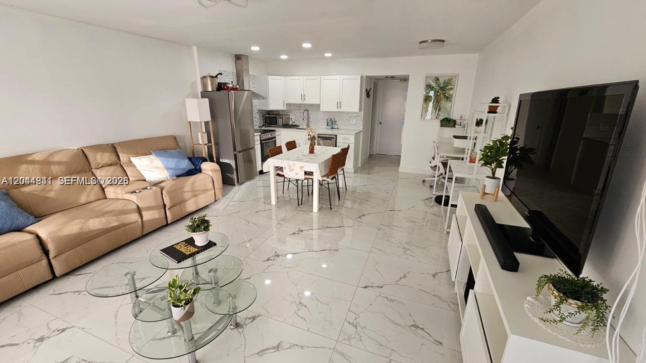 An open-concept living and dining area features white cabinets, marble-look tile floors, and a sofa — 340 S Oakridge  S # 340, Deerfield Beach FL 33442, DEERFIELD BEACH, FL