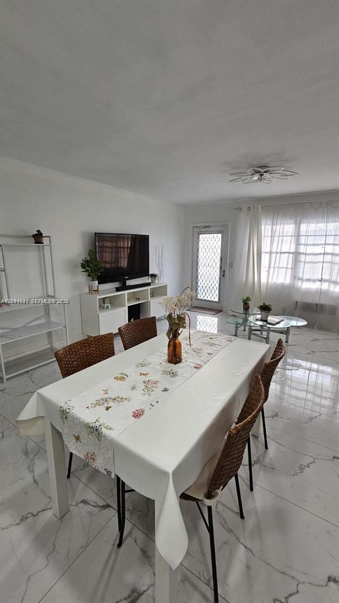A dining area with a white table and woven chairs sits in a tiled room — 340 S Oakridge  S # 340, Deerfield Beach FL 33442, DEERFIELD BEACH, FL