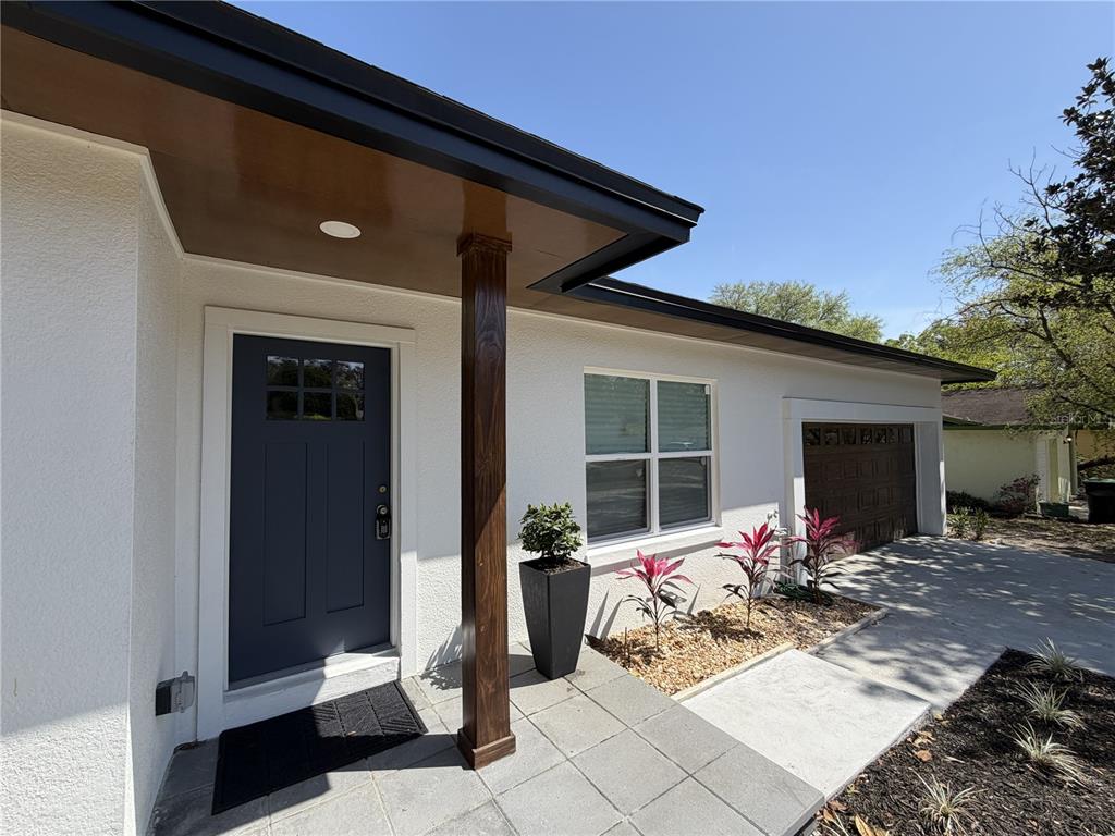 The exterior of a house features a blue front door, a wooden post, and a garage — 2235 WAUTOMA PLACE, ORLANDO, FL
