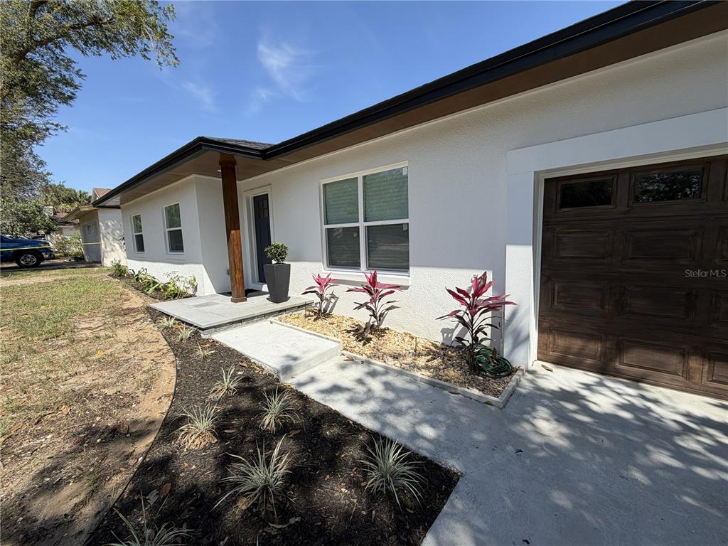The exterior of a white house features a wooden garage door and a front porch — 2235 WAUTOMA PLACE, ORLANDO, FL