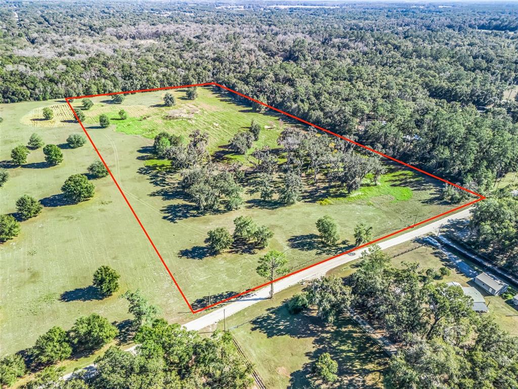 An aerial view shows a large, rectangular grassy lot outlined in red bordering a road — TBD NW 127 COURT, OCALA, FL