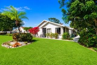 A single-story house with a white exterior sits behind a large, green front lawn — 3010 NW 12th St # D, Delray Beach FL 33445, DELRAY BEACH, FL
