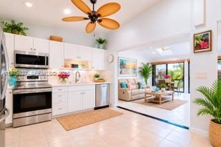 A bright kitchen with white cabinets and stainless steel appliances opens into a living area — 3010 NW 12th St # D, Delray Beach FL 33445, DELRAY BEACH, FL