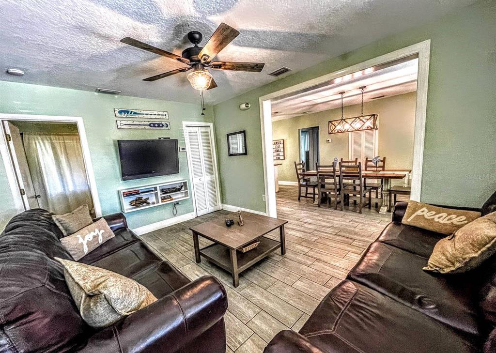 A living room with dark leather sofas, a coffee table, and a view into the dining room — 42 SOMERSET STREET, CLEARWATER BEACH, FL