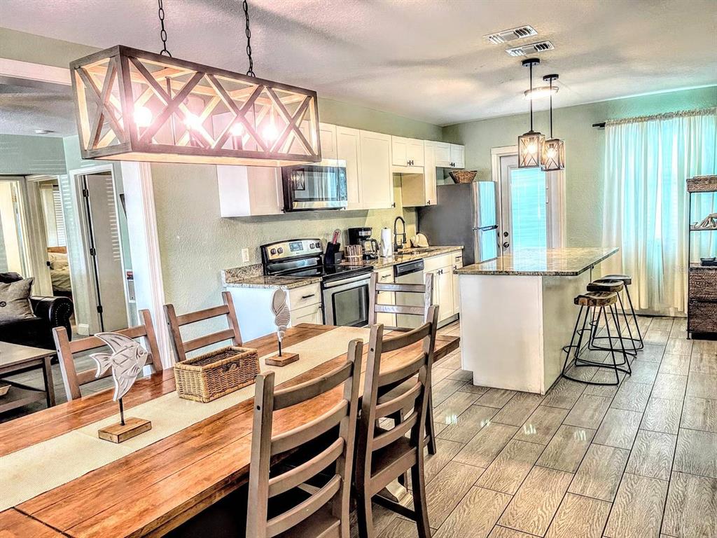 A kitchen and dining area with wooden furniture, white cabinets, and a kitchen island — 42 SOMERSET STREET, CLEARWATER BEACH, FL