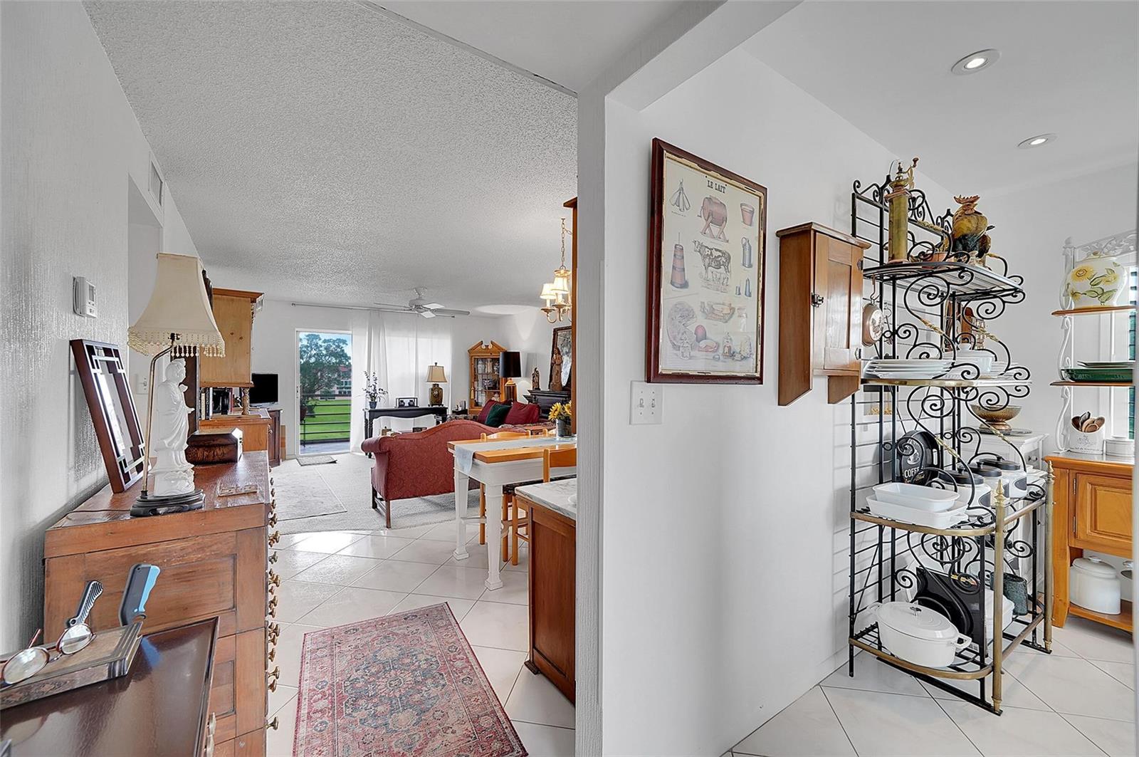 A view from a tiled entryway looking into a living room with a sliding door — 9481 Sunrise Lakes Boulevard # 310, Sunrise FL 33322, SUNRISE, FL