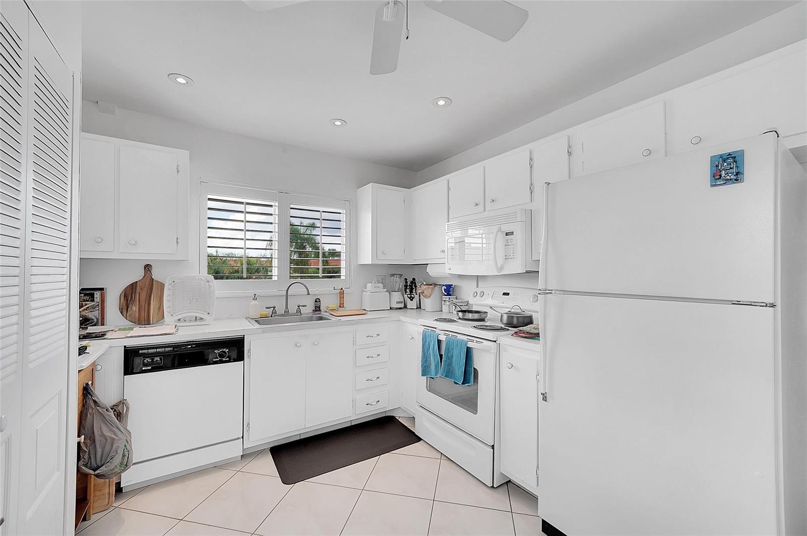 A white kitchen features white cabinetry, a dishwasher, a stove, and a refrigerator — 9481 Sunrise Lakes Boulevard # 310, Sunrise FL 33322, SUNRISE, FL