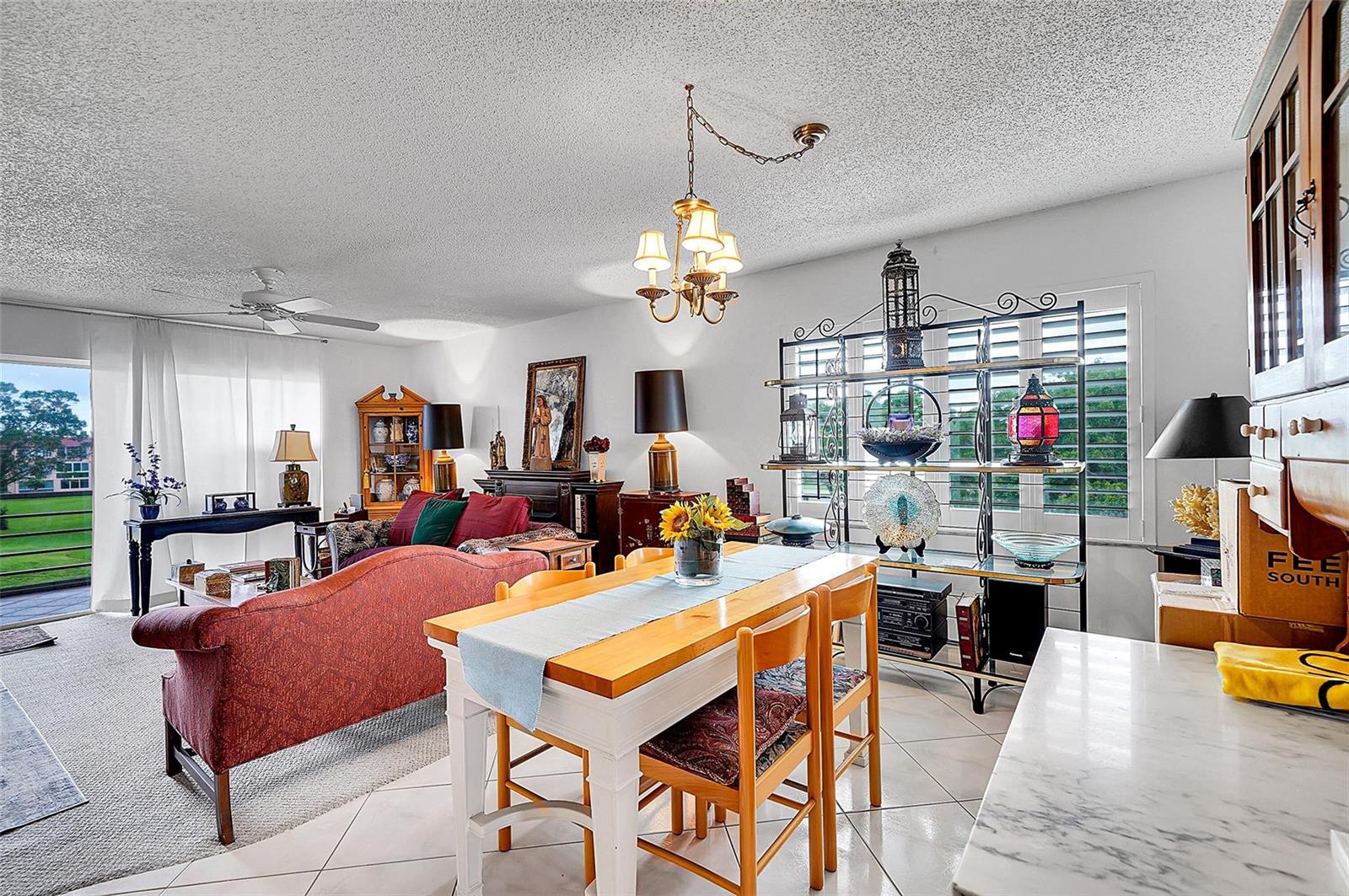 A living and dining area features a red sofa, wooden dining table, and a balcony view — 9481 Sunrise Lakes Boulevard # 310, Sunrise FL 33322, SUNRISE, FL