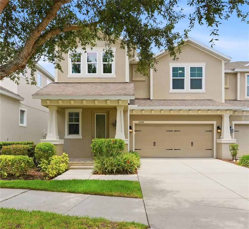 A two-story suburban house features a tan stucco exterior, a front porch, and a garage — 14508 ROCKY BROOK DRIVE, TAMPA, FL