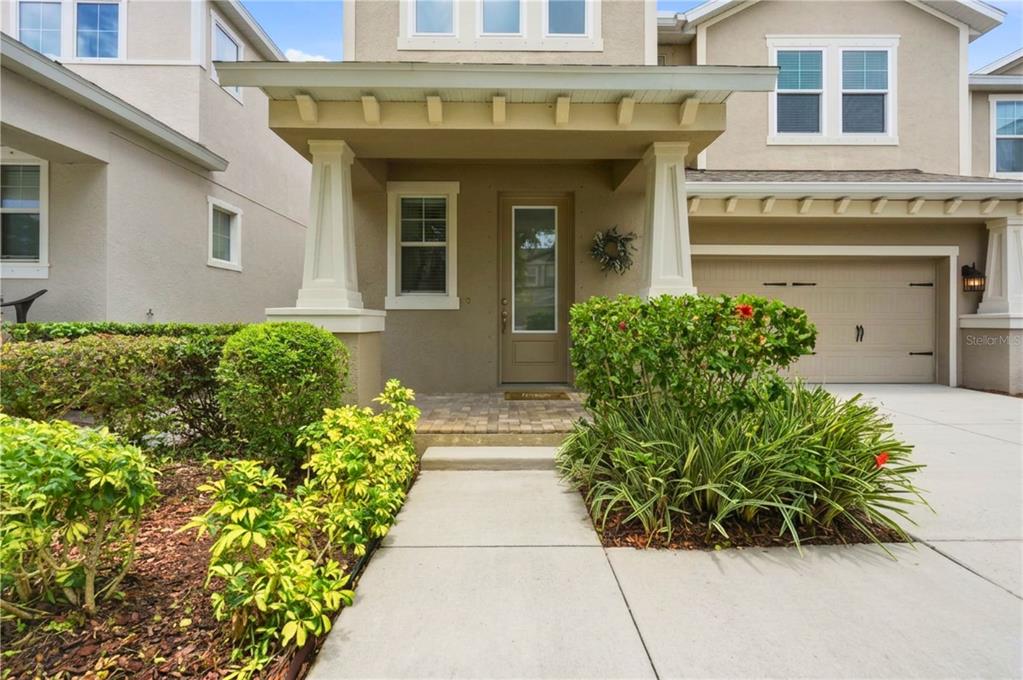 The exterior of a two-story tan house features a covered front porch and driveway — 14508 ROCKY BROOK DRIVE, TAMPA, FL