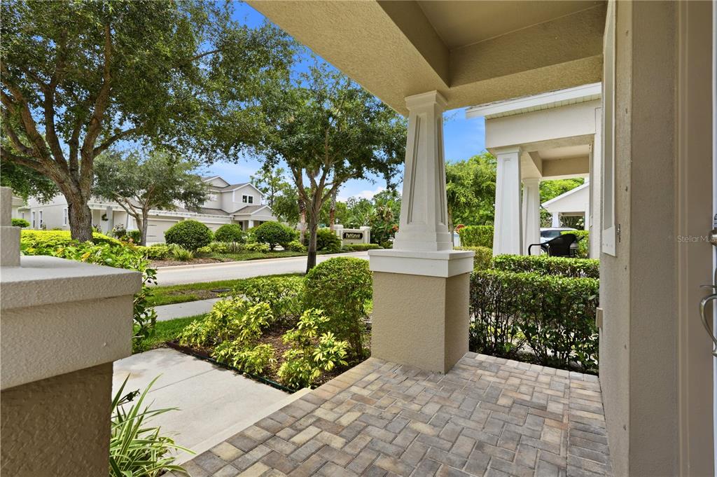A covered front porch with stone pavers overlooks a landscaped neighborhood street — 14508 ROCKY BROOK DRIVE, TAMPA, FL
