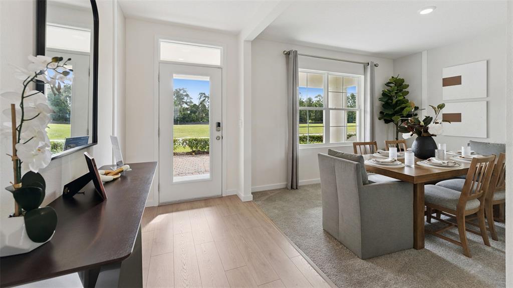 A dining area with a wooden table and chairs sits beside a bright entryway — 1126 GULL DRIVE, APOPKA, FL