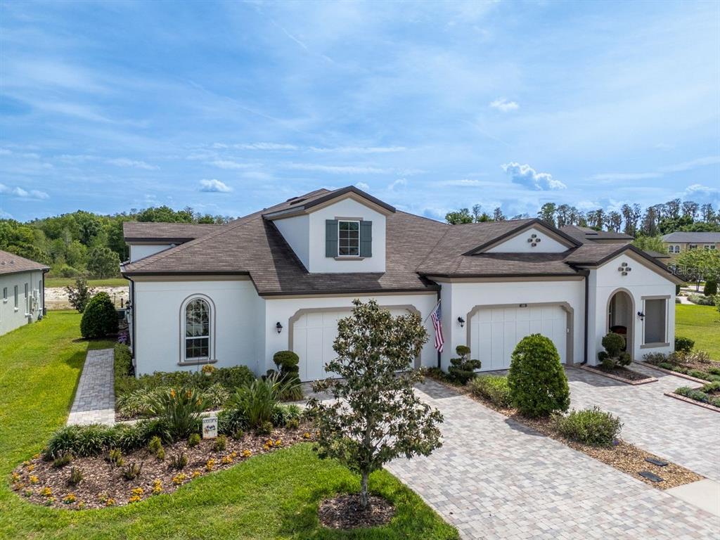 A white, single-story house with a brown shingled roof, two garage doors, and a paved driveway — 4170 BARLETTA COURT, WESLEY CHAPEL, FL