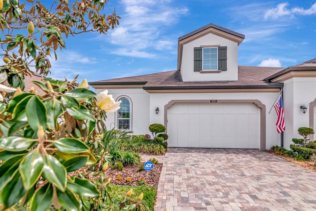 A white house exterior features a two-car garage, a dormer window, and a paved driveway — 4170 BARLETTA COURT, WESLEY CHAPEL, FL