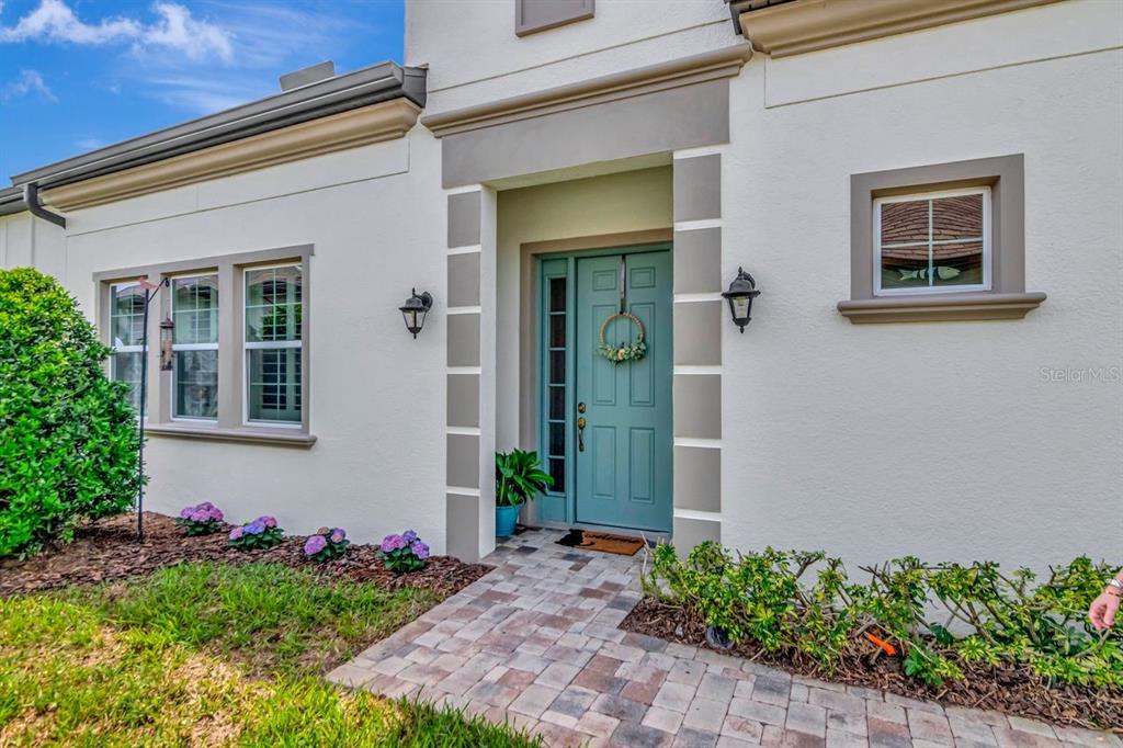 The exterior of a house features a teal front door, stone walkway, and landscaping — 4170 BARLETTA COURT, WESLEY CHAPEL, FL