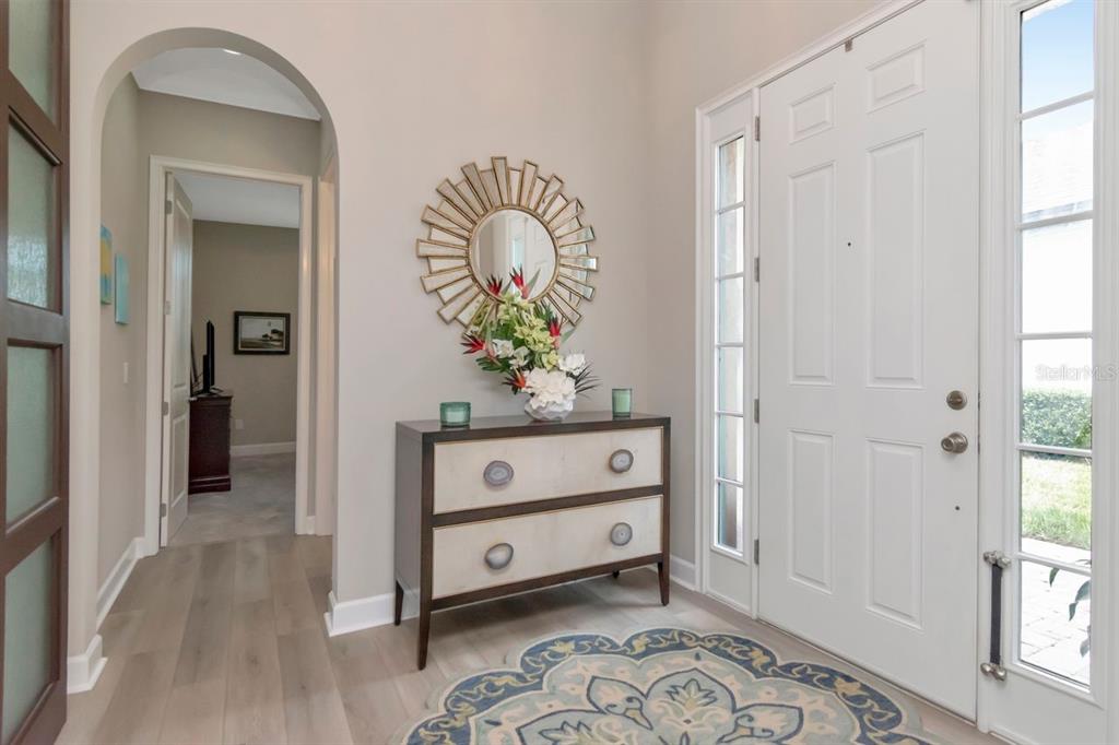 A foyer features a white front door, a two-drawer chest, and a sunburst mirror — 4170 BARLETTA COURT, WESLEY CHAPEL, FL