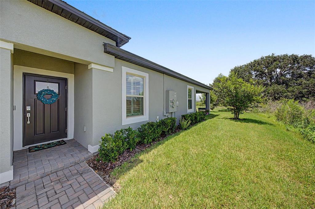 The exterior of a house features a dark front door, a brick walkway, and landscaping — 32092 CANNON RUSH DRIVE, SAN ANTONIO, FL