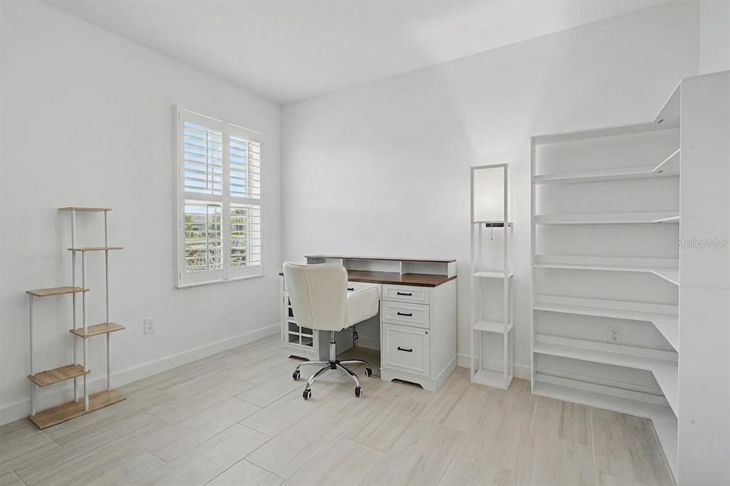 A home office features white walls, light tile flooring, a desk, a chair, and shelving — 32092 CANNON RUSH DRIVE, SAN ANTONIO, FL