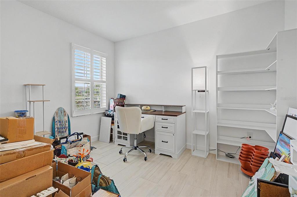A home office features a white desk, a chair, shelving, and boxes on the floor — 32092 CANNON RUSH DRIVE, SAN ANTONIO, FL