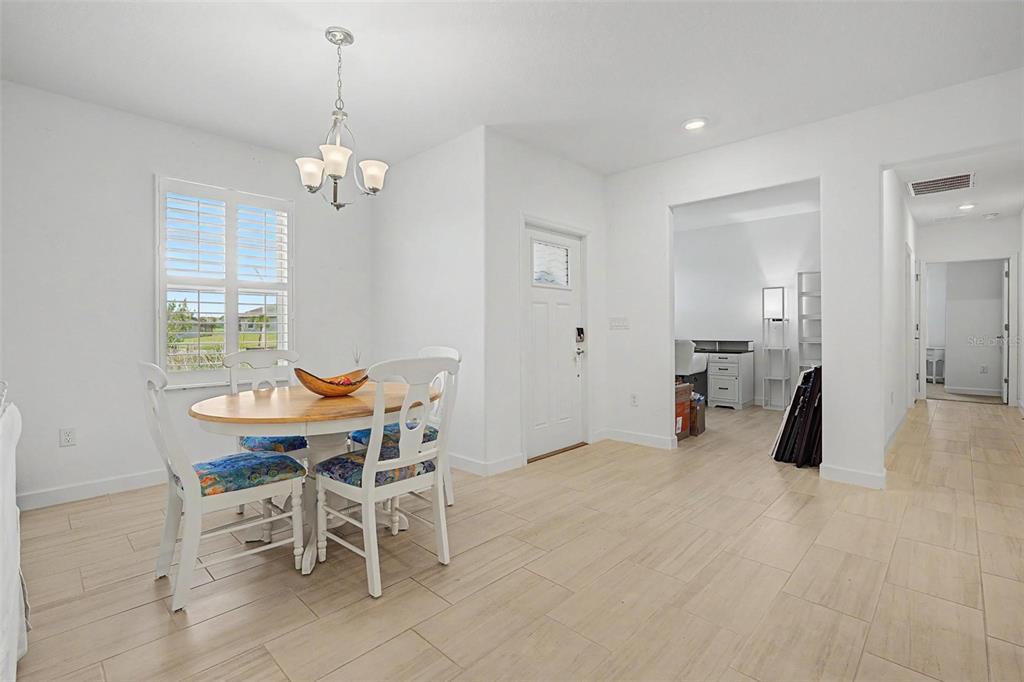 A dining area with a round wooden table, white chairs, and tile flooring — 32092 CANNON RUSH DRIVE, SAN ANTONIO, FL