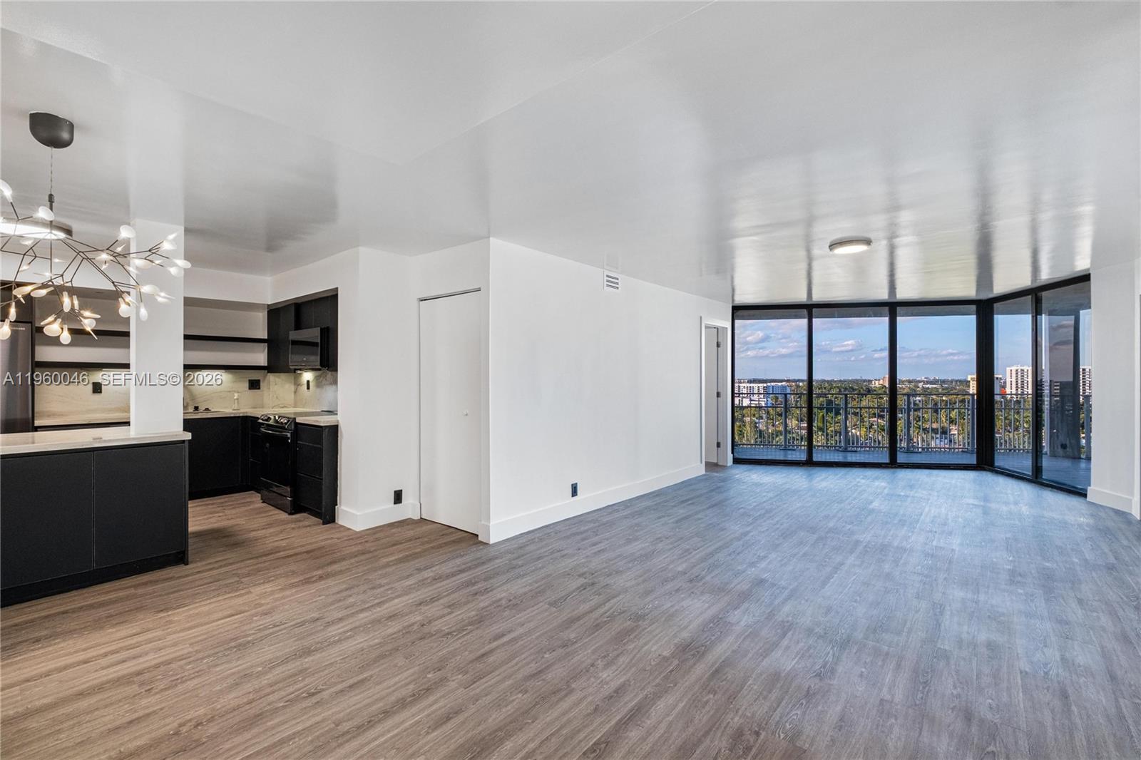 An open-concept living area features dark kitchen cabinetry, wood-look flooring, and floor-to-ceiling balcony windows — 4000 Towerside Ter # 1509, Miami FL 33138, MIAMI, FL