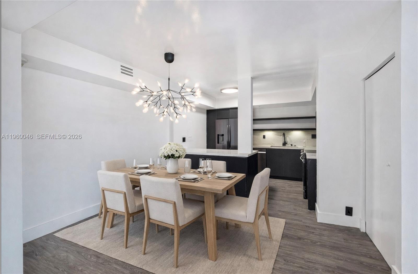 A dining area with a modern chandelier sits adjacent to a kitchen with dark cabinetry — 4000 Towerside Ter # 1509, Miami FL 33138, MIAMI, FL