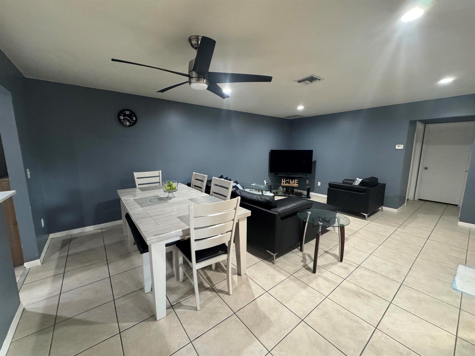 A dining area and living room with dark blue walls, tile flooring, and black furniture — 8016 AMBACH Way # 18D, Hypoluxo FL 33462, HYPOLUXO, FL