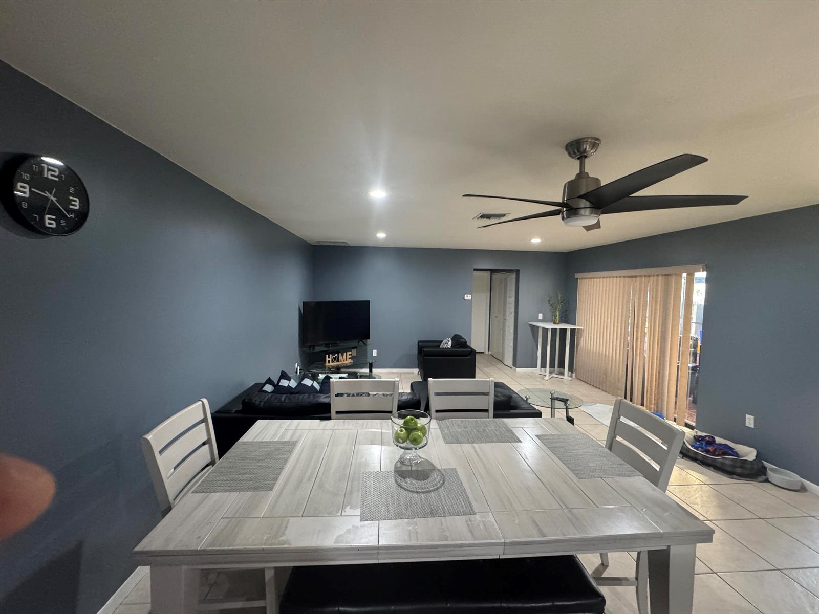 A dining area with a light wood table sits in front of a blue-walled living room — 8016 AMBACH Way # 18D, Hypoluxo FL 33462, HYPOLUXO, FL