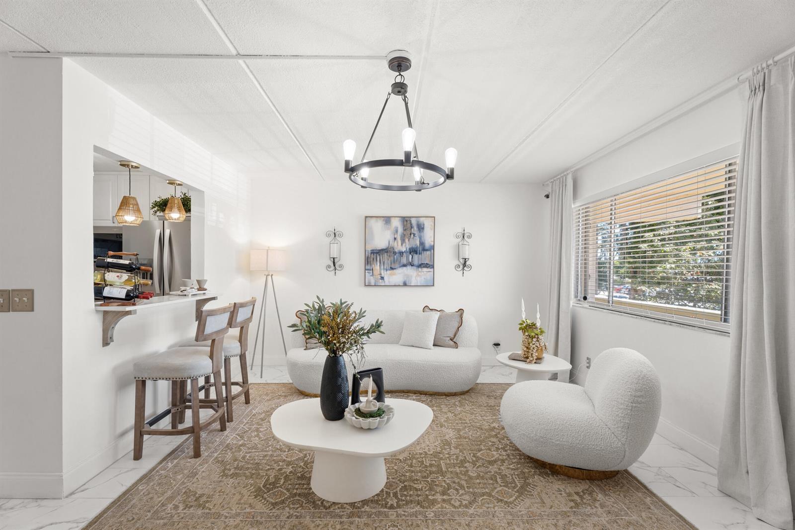 A bright living room features a white sofa, a round chair, and a breakfast bar — 200 Village Green Circle E # 206, Palm Springs FL 33461, PALM SPRINGS, FL