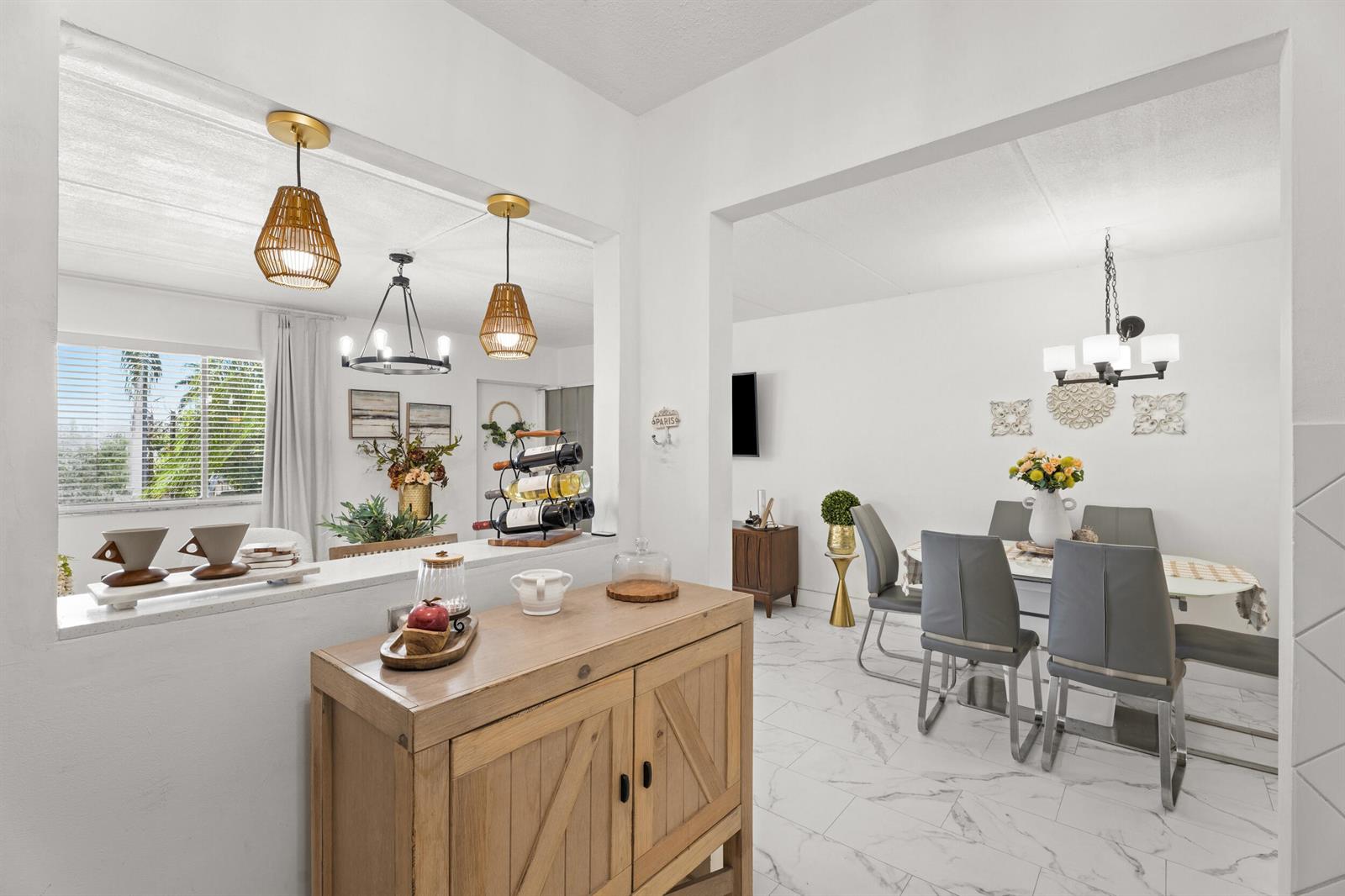 A dining room and adjacent living area feature white walls, marble-look tile floors, and pendant lighting — 200 Village Green Circle E # 206, Palm Springs FL 33461, PALM SPRINGS, FL