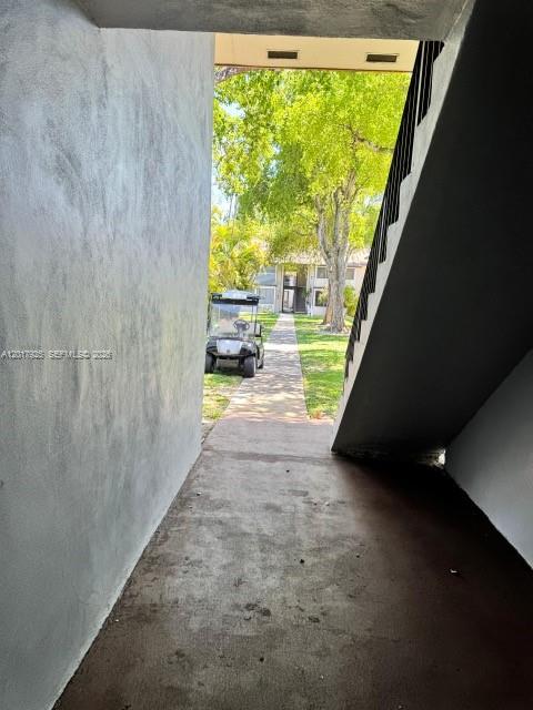 A concrete walkway leads past a staircase toward a golf cart parked outdoors — 380 E Laurel Dr # 4D, Margate FL 33063, MARGATE, FL