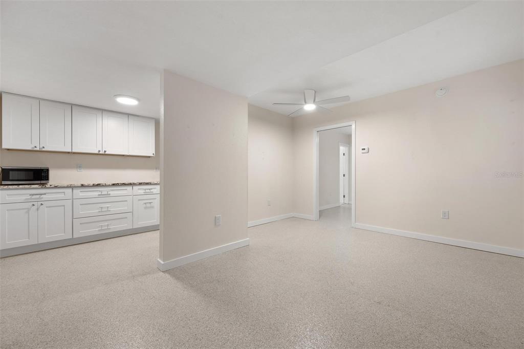A kitchen with white cabinets and a microwave opens into a carpeted living area — 308 OHIO PLACE UNIT 1, SARASOTA, FL