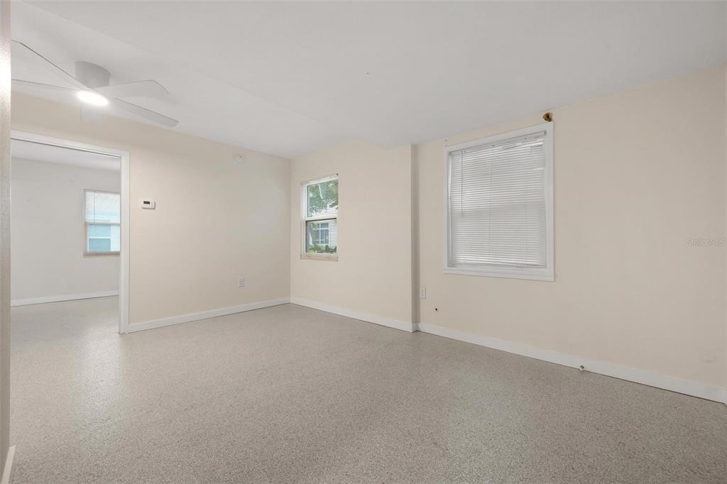 An empty room with beige walls, light-colored flooring, two windows, and a ceiling fan — 308 OHIO PLACE UNIT 1, SARASOTA, FL
