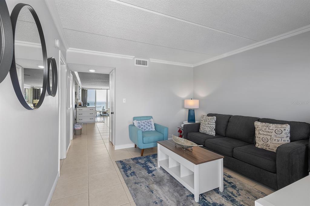 A living room features a dark sofa, a blue armchair, a coffee table, and tile flooring — 2401 S ATLANTIC AVENUE UNIT A603, NEW SMYRNA BEACH, FL