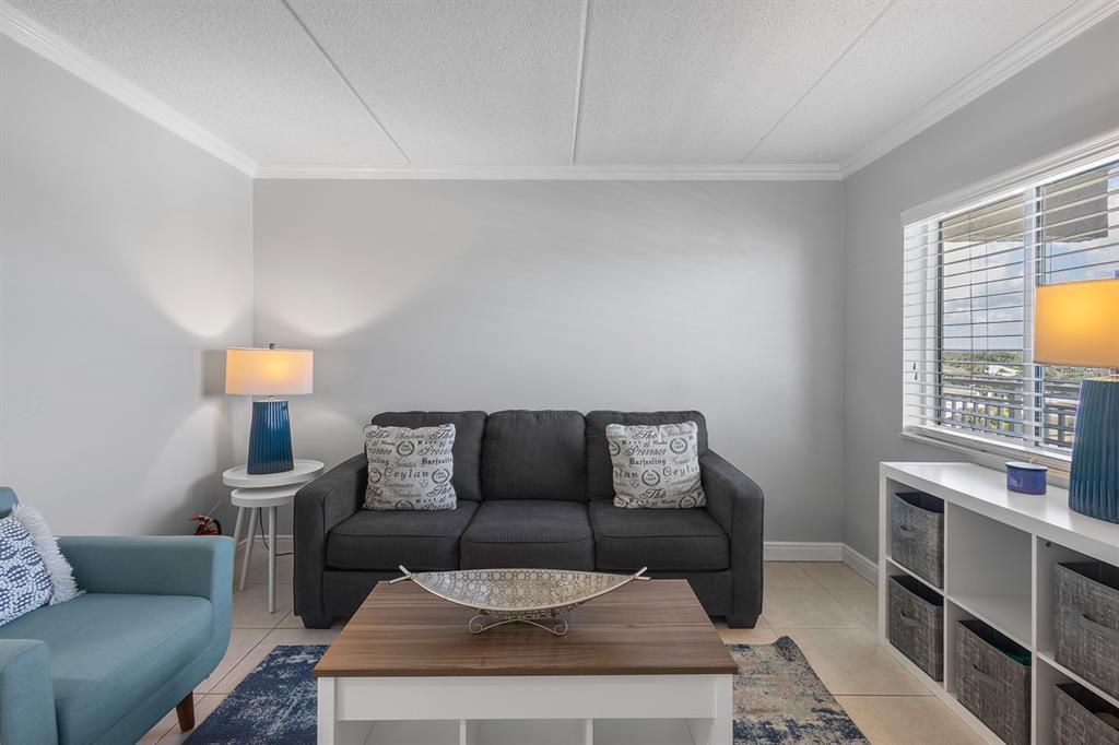 A living room features a dark gray sofa, a blue armchair, and a coffee table — 2401 S ATLANTIC AVENUE UNIT A603, NEW SMYRNA BEACH, FL