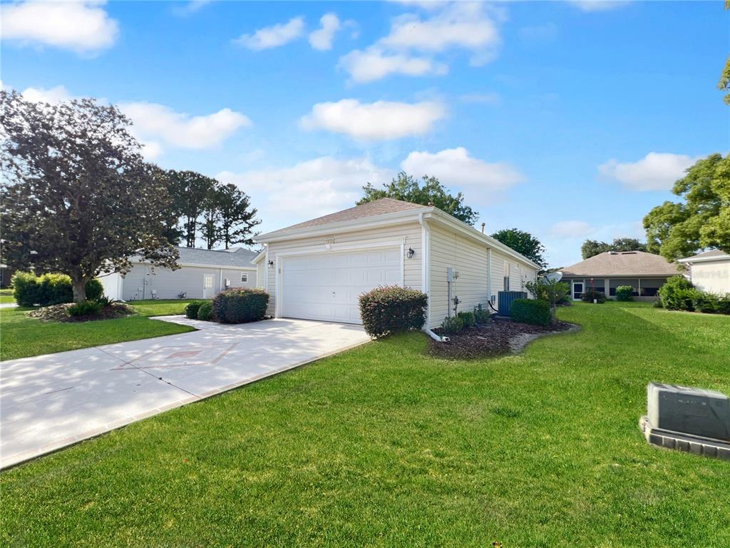 A beige detached garage with a white door sits on a grassy lot — 13150 SE 93RD CIRCLE, SUMMERFIELD, FL