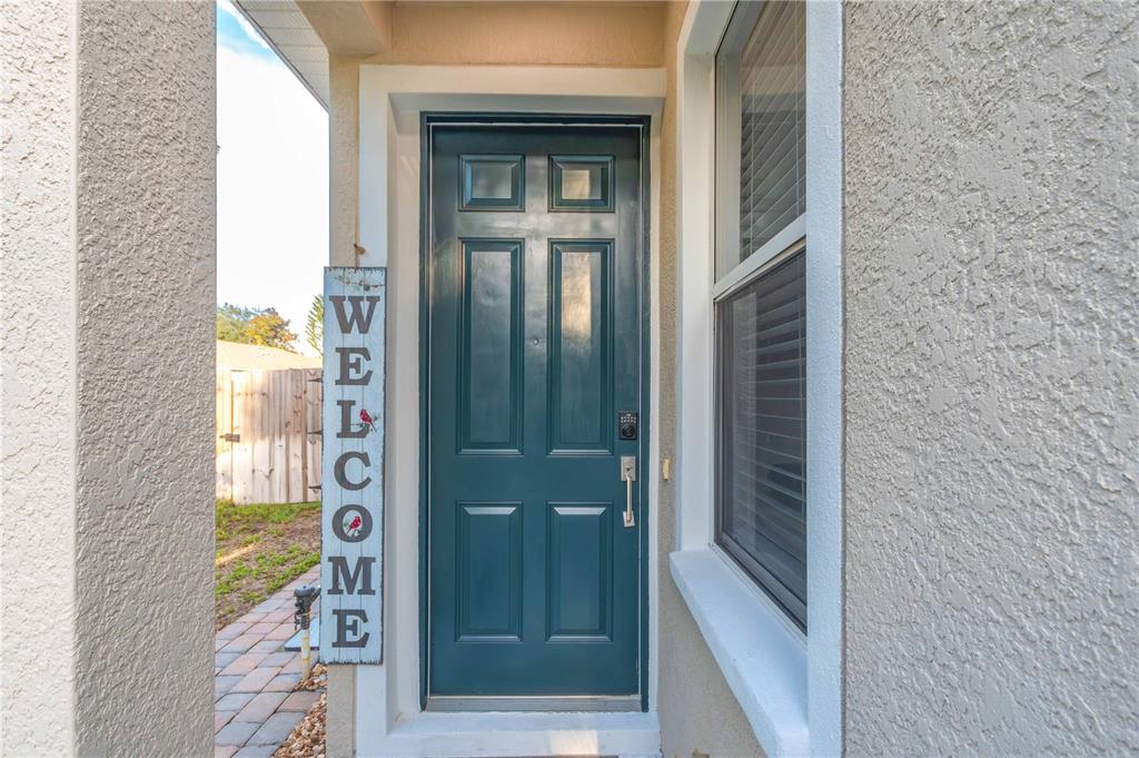 A teal front door with a welcome sign stands at the entrance of a home — 9644 SIMEON DRIVE, LAND O LAKES, FL