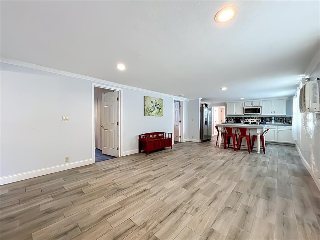 An open-concept room features light gray walls, wood-look tile flooring, and a kitchen with island seating — 1119 CYPRESS AVENUE, SANFORD, FL