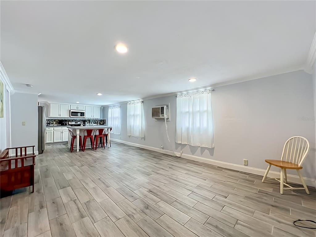 An open-concept kitchen and living area features light wood-look tile flooring and white cabinetry — 1119 CYPRESS AVENUE, SANFORD, FL