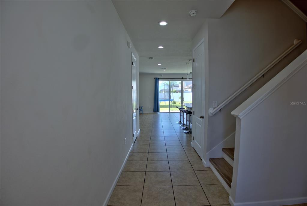 A tiled hallway leads from the entryway toward a kitchen and sliding glass patio doors — 3576 BRISTOL COVE LANE, ST CLOUD, FL