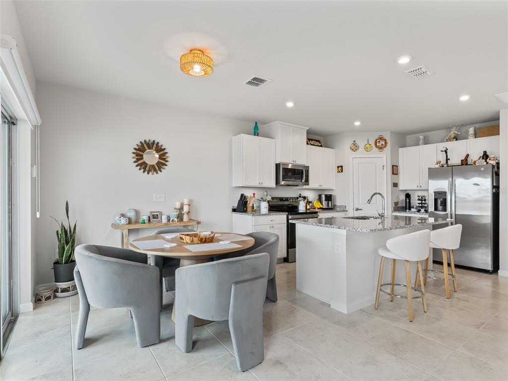 A kitchen and dining area with white cabinets, a central island, and gray upholstered chairs — 2133 TENNESSEE STREET, SUMTERVILLE, FL