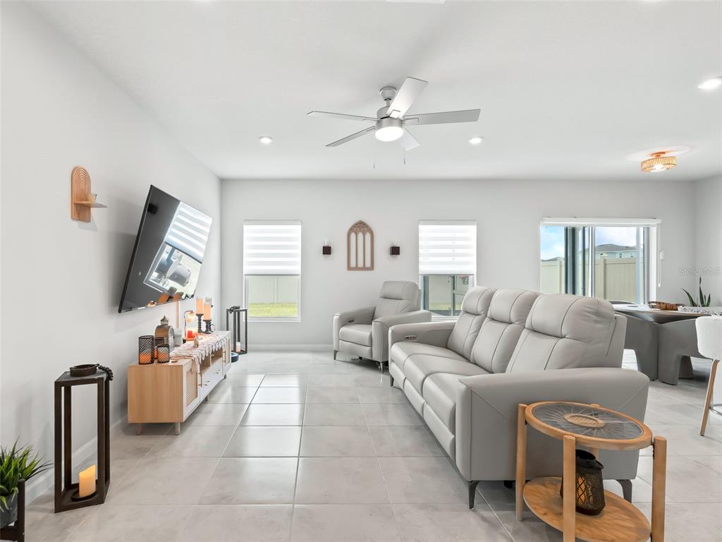 A living room features light gray tile floors, a leather sofa, and a wall-mounted television — 2133 TENNESSEE STREET, SUMTERVILLE, FL