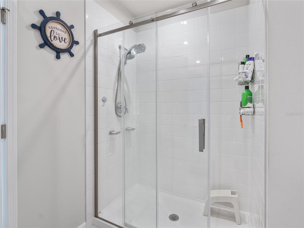 A walk-in shower with white subway tile walls and a sliding glass door — 2133 TENNESSEE STREET, SUMTERVILLE, FL